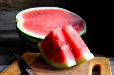 Karpuz, dilimlenmiş, bıçak, mutfak tahtası eski bir rustik masada.