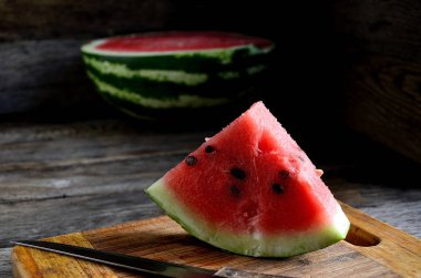 Karpuz, dilimlenmiş, bıçak, mutfak tahtası eski bir rustik masada.