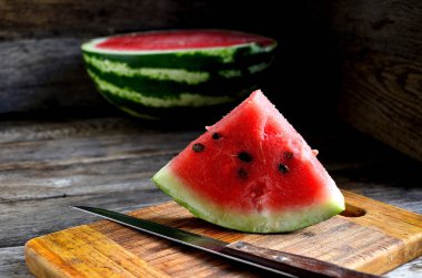 Karpuz, dilimlenmiş, bıçak, mutfak tahtası eski bir rustik masada.