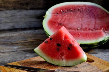 Karpuz, dilimlenmiş, bıçak, mutfak tahtası eski bir rustik masada.