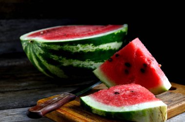 Karpuz, dilimlenmiş, bıçak, mutfak tahtası eski bir rustik masada.