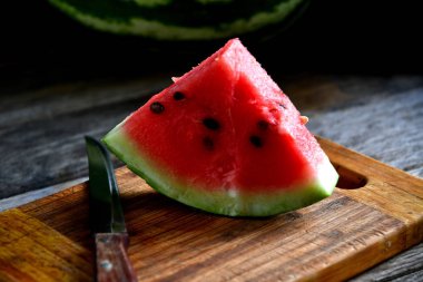 Karpuz, dilimlenmiş, bıçak, mutfak tahtası eski bir rustik masada.