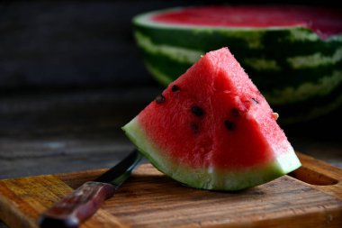 Karpuz, dilimlenmiş, bıçak, mutfak tahtası eski bir rustik masada.