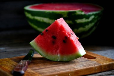 Karpuz, dilimlenmiş, bıçak, mutfak tahtası eski bir rustik masada.