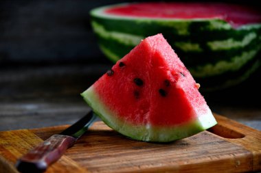Karpuz, dilimlenmiş, bıçak, mutfak tahtası eski bir rustik masada.