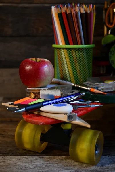 School supplies located on a skateboard.