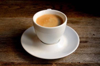 Eski tahtalarda beyaz bir fincan kahve.