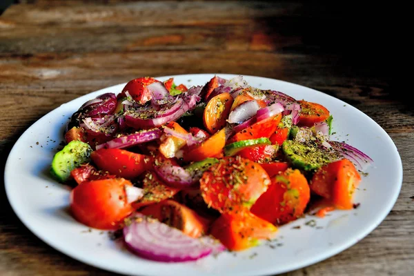 トマト キュウリ スパイス ハーブの夏のサラダを木製のテーブルの上の白い皿に — ストック写真