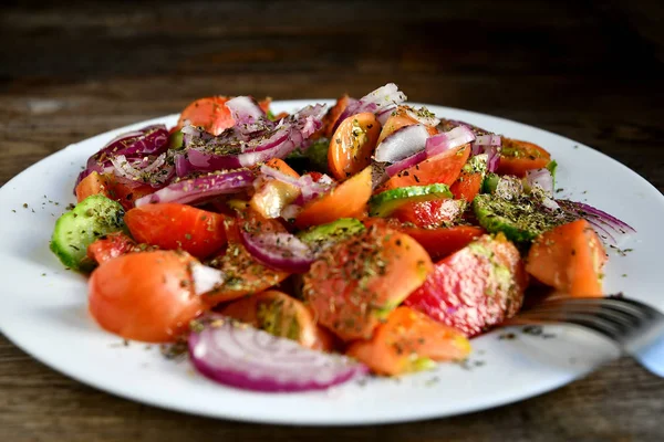 トマト キュウリ スパイス ハーブの夏のサラダを木製のテーブルの上の白い皿に — ストック写真