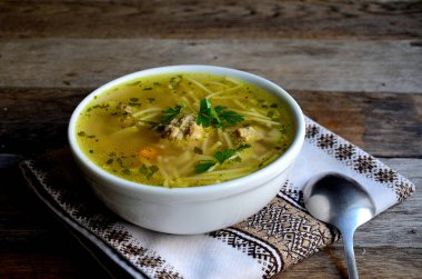 Köfte ve erişte ile ev yapımı çorba, ahşap bir masada halk peçete.