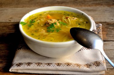 Köfte ve erişte ile ev yapımı çorba, ahşap bir masada halk peçete.