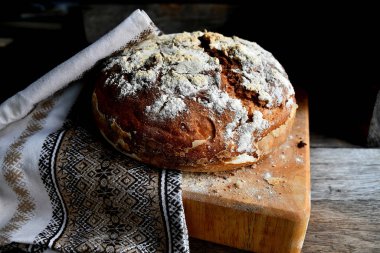 Ev yapımı ekmek bir halk, ulusal peçete mutfak, ahşap bir masa üzerinde bir mutfak tahtası üzerinde yatıyor.
