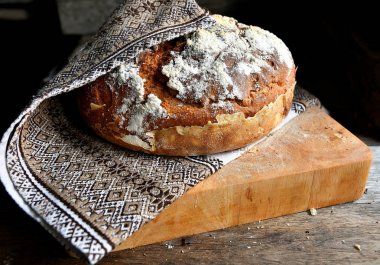 Ev yapımı ekmek bir halk, ulusal peçete mutfak, ahşap bir masa üzerinde bir mutfak tahtası üzerinde yatıyor.