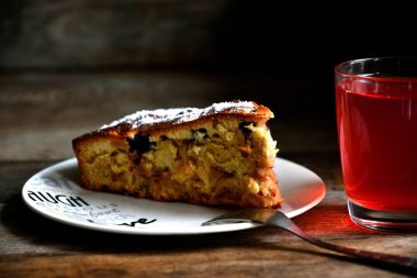 Charlotte beyaz bir tabak, çatal ve ahşap bir masa üzerinde elma kompostosu.