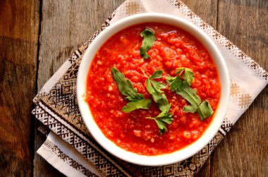 Beyaz bir kase ev adjika, folklor, eski kurulların arka planda ulusal peçete.