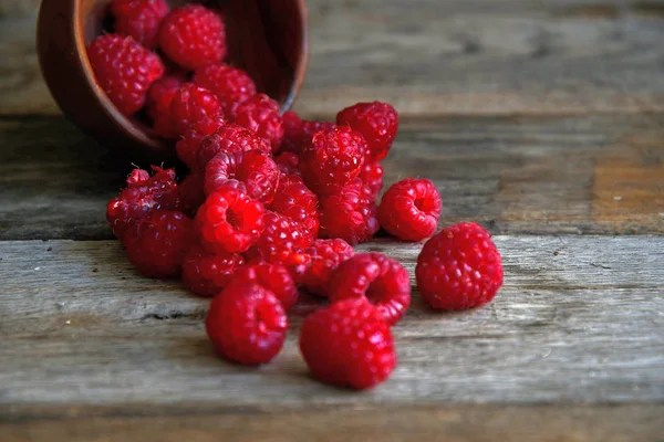 Tipped raspberries scattered on wooden boards from wooden utensils.