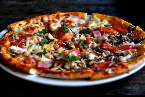 Eski kurulları bir arka plan üzerinde beyaz bir kapta peynir, pastırma, domates ve otlar ile Pizza.