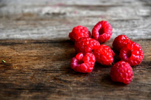 Tipped raspberries scattered on old wooden boards.
