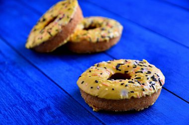 Mutfakta mavi bir arka plan üzerinde iştah açıcı donutlar.
