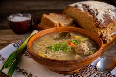 Kil seramik kasede köfteli çorba, eski ahşap bir masada peçete..