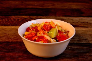 Eski tahtaların arka planında beyaz bir ayak parmağında sebze salatası..