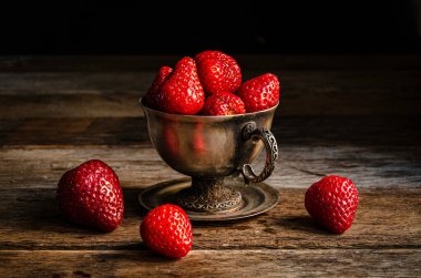 Tahta tahtalardaki gümüş bardakta çilekler..