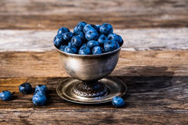 Gümüş bir tabakta siyah dağ külleri kırsal bir ahşap masada duruyor..