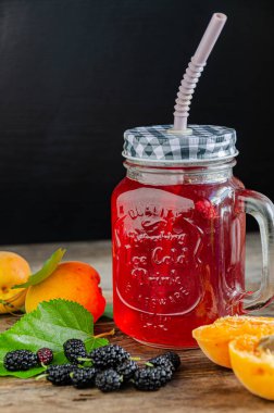 Ev yapımı, kayısı kompostosu ve eski ahşap tahtaların üzerinde pipetle birlikte dut bardağı..