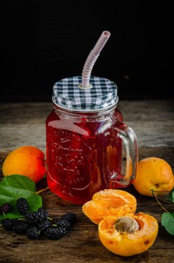 Ev yapımı, kayısı kompostosu ve eski ahşap tahtaların üzerinde pipetle birlikte dut bardağı..