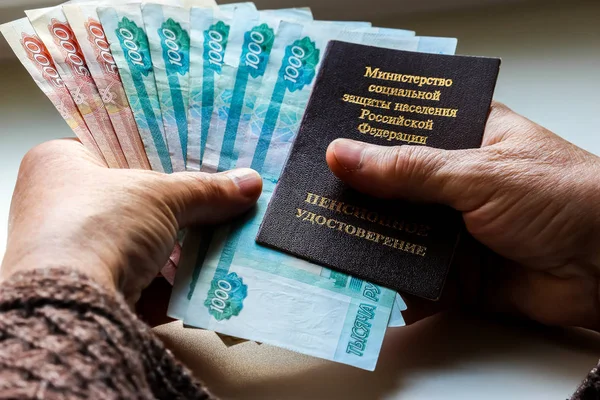 妇女的手持有俄罗斯养老金证书和俄罗斯卢布 俄罗斯翻译 俄罗斯联邦人口社会保护部 养老金证书 — 图库照片