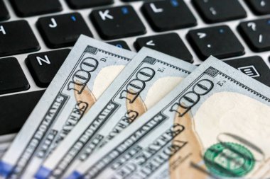 Yüz dolarlık banknotlar laptop klavye üzerinde yalan closeup görünümü.