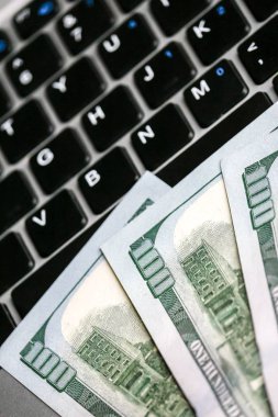 Yüz dolarlık banknotlar laptop klavye üzerinde yalan closeup görünümü.