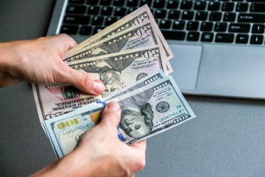 Yüz elli doları banknot, laptop klavye arka planda tutan el.