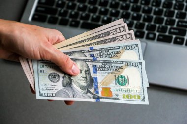 Yüz elli doları banknot, laptop klavye arka planda tutan el.