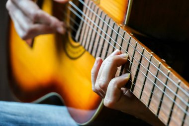 Akustik gitar çalan müzisyenlerin yakın görüntüsü.