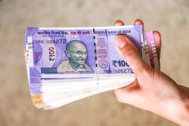 Woman's hands holding brand new indian 100, 200, 500, 2000 rupees banknotes. clipart