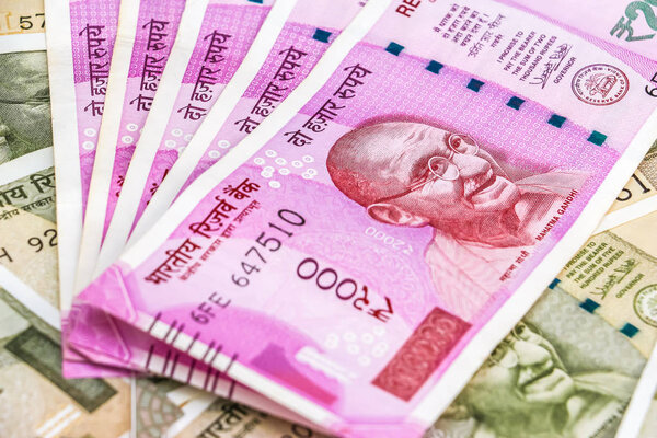 Закрыть вид на новенькие индийские банкноты 2000 рупий. Банкноты в 500 рупий на заднем плане
.