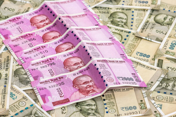 Закрыть вид на новенькие индийские банкноты 2000 рупий. Банкноты в 500 рупий на заднем плане
.