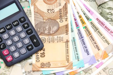 Hesap makinesinin görüntüsünü 10, 50, 100, 200, 500 ve 2000 rupilik banknotlar üzerine kapatın. Renkli para arkaplanı.