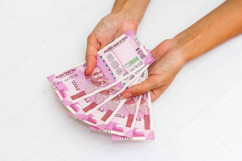 Female hands holding brand new 2000 indian rupees banknotes.