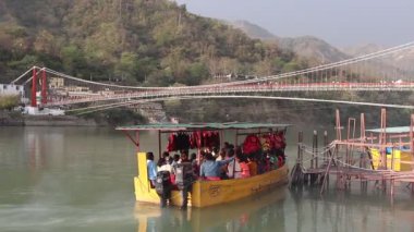 Rishikesh, Hindistan - Mart 2019. Rishikesh Ganga nehir dolgu güzel görünümü. İnsanlar Ganga nehrini tekneyle geçiyorlar.