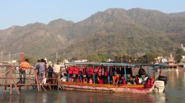 Rishikesh, Hindistan - Mart 2019. Rishikesh Ganga nehir dolgu güzel görünümü. İnsanlar Ganga nehrini tekneyle geçiyorlar.