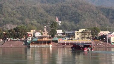 Rishikesh, Hindistan - Mart 2019. Rishikesh Ganga nehir dolgu güzel görünümü. İnsanlar Ganga nehrini tekneyle geçiyorlar.