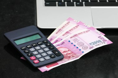 Yepyeni hint 2000 rupi banknotlar, elektronik hesap makinesi ve dizüstü yakından görünümü.