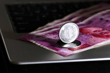 Yepyeni Hint 2000 rupi banknotlar ve laptop üzerinden bir Rupisi sikke yakın yukarı görünümü.