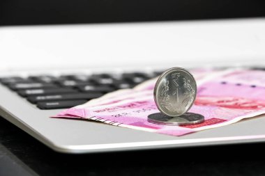 Yepyeni Hint 2000 rupi banknotlar ve laptop üzerinden bir Rupisi sikke yakın yukarı görünümü.
