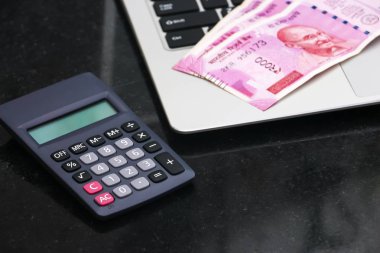 Yepyeni hint 2000 rupi banknotlar, elektronik hesap makinesi ve dizüstü yakından görünümü.