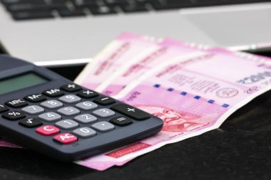 Yepyeni hint 2000 rupi banknotlar, elektronik hesap makinesi ve dizüstü yakından görünümü.