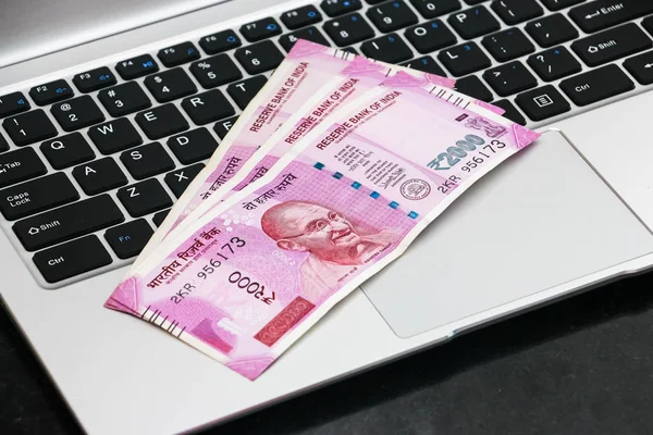 Yepyeni Hint banknotlarının ve dizüstü bilgisayarların yakın görüntüsü.