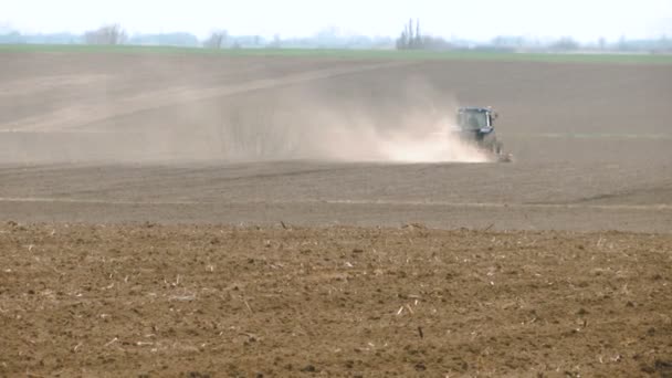 在他身后有尘埃云的田野里的拖拉机 春天的土壤准备 — 图库视频影像